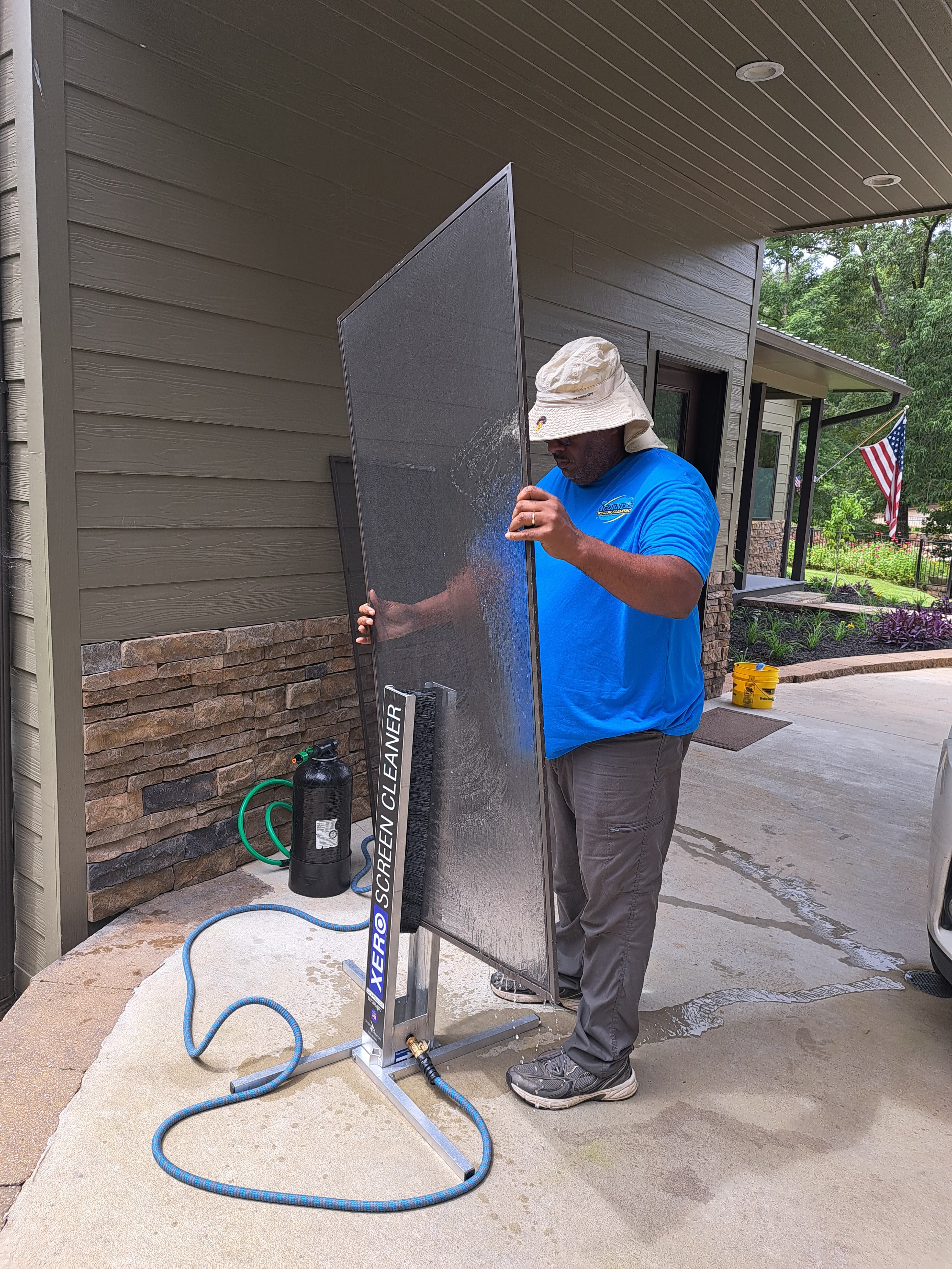 Man in blue shirt cleaning a large window screen with a professional Xero Screen Cleaner.